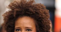 Wanda Sykes with curly hair, wearing a black jacket and earrings, smiling confidently at an outdoor event.