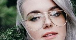Young woman with long silver hair and glasses, surrounded by greenery, showcasing a natural and stylish look.