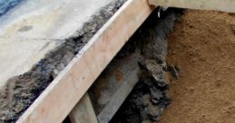 Excavation site showing wooden supports and exposed pipes, essential for construction and main work foundation stability.