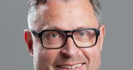 Ludovic Van Eeckhoven smiling in a professional setting, wearing a dark suit and glasses against a neutral background.