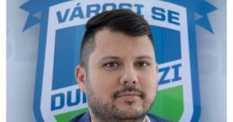 Pasku Balázs, operational leader of Városi SE, poses against the club emblem, showcasing professionalism and team spirit.
