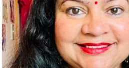 Woman in a red outfit with jewelry, smiling with hands in a prayer position, showcasing positivity and cultural expression.