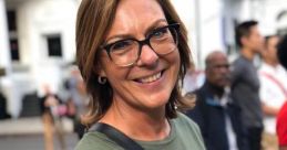 Smiling woman in a green shirt with "Crown" design, showcasing style and confidence in a lively urban setting.