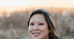 Linda Giang smiles confidently in her professional dental attire against a natural backdrop, embodying dedicated patient care.