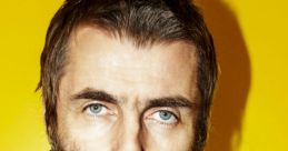 Liam Gallagher in a dark jacket against a bright yellow background, showcasing his signature style and intense gaze.