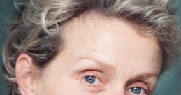 Close-up portrait of Frances McDormand showcasing her expressive blue eyes and signature tousled hair against a soft background.
