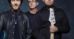 Pearl Jam band members pose together, showcasing their iconic style and instruments in a casual, artistic setting.