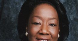 Professional portrait of a woman wearing a black blazer and pearl necklace, smiling against a blue backdrop.