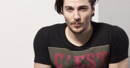 Stylish young man with tousled hair, wearing a graphic tee, exuding modern Persian fashion vibes in a subtle, artistic setting.