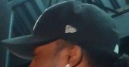 Man with a baseball cap and earrings, smiling, in a dimly lit setting, expressing excitement or joy. Shouting Tony.