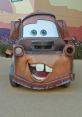 Tow Mater, the lovable truck from Cars, shows off his cheerful smile and big, expressive eyes in a vibrant setting.