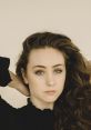 Chappell Roan showcases her unique style with elegant curls and striking blue eyes against a minimalistic backdrop.