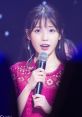 IU performing live, showcasing her soft voice and captivating presence on stage in a stunning pink outfit.