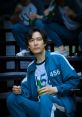 Seong Gi-hun wearing tracksuit 456, sitting on steps, holding a drink, showcasing intense expressions from Squid Game.