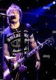 Martin Johnson from Boys Like Girls performing passionately on stage, guitar in hand, wearing a branded t-shirt.