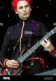 Matthew Bellamy performing live with a guitar, showcasing his iconic red hairstyle and energetic stage presence.