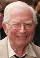 David Croft, F1 commentator, smiling warmly with glasses at a public event, showcasing a friendly demeanor.