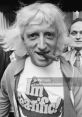 Jimmy Savile in a bold "I'm Tearific!" shirt, showcasing his flamboyant style and personality in a candid moment.