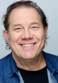 Fred Tatasciore, voice actor known for Megatron in Cybertron games, smiles warmly in a casual denim jacket.