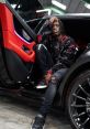 Kai Cenat posing stylishly in a luxury car, showcasing his trendy outfit and urban fashion sense.