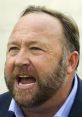 Alex Jones passionately addresses the crowd, showcasing his intense expression and distinctive beard during an event.