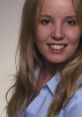 Smiling young woman with blonde hair and a blue shirt, exuding confidence and approachability in a professional setting.