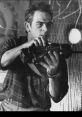 Chip Hazard, portrayed by Tommy Lee Jones, holds a weapon, showcasing intensity and readiness for action in this scene.