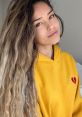 Valkyrae smiles in a cozy yellow hoodie, showcasing her signature style and radiant personality.