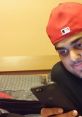 Person wearing a red cap sits on a bed, focused on a phone, exploring content related to gaming and entertainment.