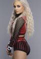 Liv Morgan poses confidently, showcasing her stylish wrestling gear with a striking red and black design and long blonde waves.