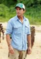 Jeff Probst in a blue shirt and green cap, poised on a beach, ready to host another exciting episode of Survivor.
