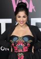 Noemi Gonzalez smiles confidently, showcasing her vibrant floral dress at a glamorous event. Perfect showcase of style.