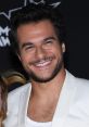 Smiling man in a stylish white jacket, showcasing charm and confidence at a glamorous event. Perfect for Amir fan pages.