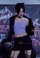 Karina flaunts an edgy look in a crop top and leather jacket, exuding confidence and allure in an urban setting.