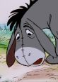 Eeyore the gloomy donkey from Winnie the Pooh, looking curiously at the ground in a lush, green setting.