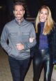Jarvis Bum enjoys a night out, smiling alongside a stylish companion in sleek outfits, showcasing a vibrant urban vibe.