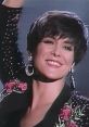 Michelle Wright smiles brightly, showcasing her signature style with floral embellishments and bold earrings on stage.