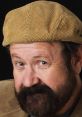Brian Cummings with a textured tan cap, sporting a beard and a friendly expression against a dark background.