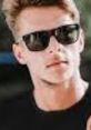 Young man with sunglasses, styled hair, and a casual outfit, embodying a laid-back summer vibe. Perfect for conversation.