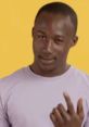 Smiling African-American man in a purple shirt, exuding charm against a vibrant yellow background.