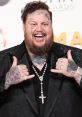 Jelly Roll flashes a joyful smile, showcasing his tattoos and flashy jewelry at a glamorous awards event.