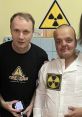 Two men pose together, showcasing "Kreosan" branding and a radiation symbol on a shirt, emphasizing safety awareness.