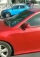 Red car parked beside a blue vehicle, capturing the vibrant urban atmosphere related to the "7000 Dollars Guy" trend.