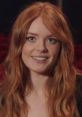 Abigail Cowen smiles brightly with flowing red hair, captivating in a theater setting.