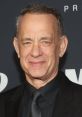 Tom Hanks smiling confidently at a red carpet event, showcasing his classic style in a black suit and tie.