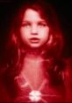 Glowing red visage of the Red Queen from Resident Evil, featuring a child-like figure with a star pendant.