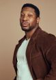 Johnathan Majors poses confidently in a stylish brown corduroy jacket, showcasing his unique fashion sense.