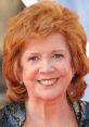 Cilla Black smiles brightly, showcasing her iconic style and vibrant red hair at a glamorous event.
