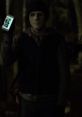 The Man from Hush 2016 holding a smartphone, wearing a mask in a dark forest setting, evoking suspenseful thriller vibes.