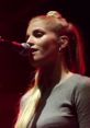 Hannah Reid performing passionately on stage, highlighting her vocal talent and stage presence under vibrant lighting.